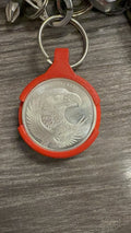 Red 3D printed Coin AirTag Hiding Keychain holding a 1 oz silver eagle round, close up