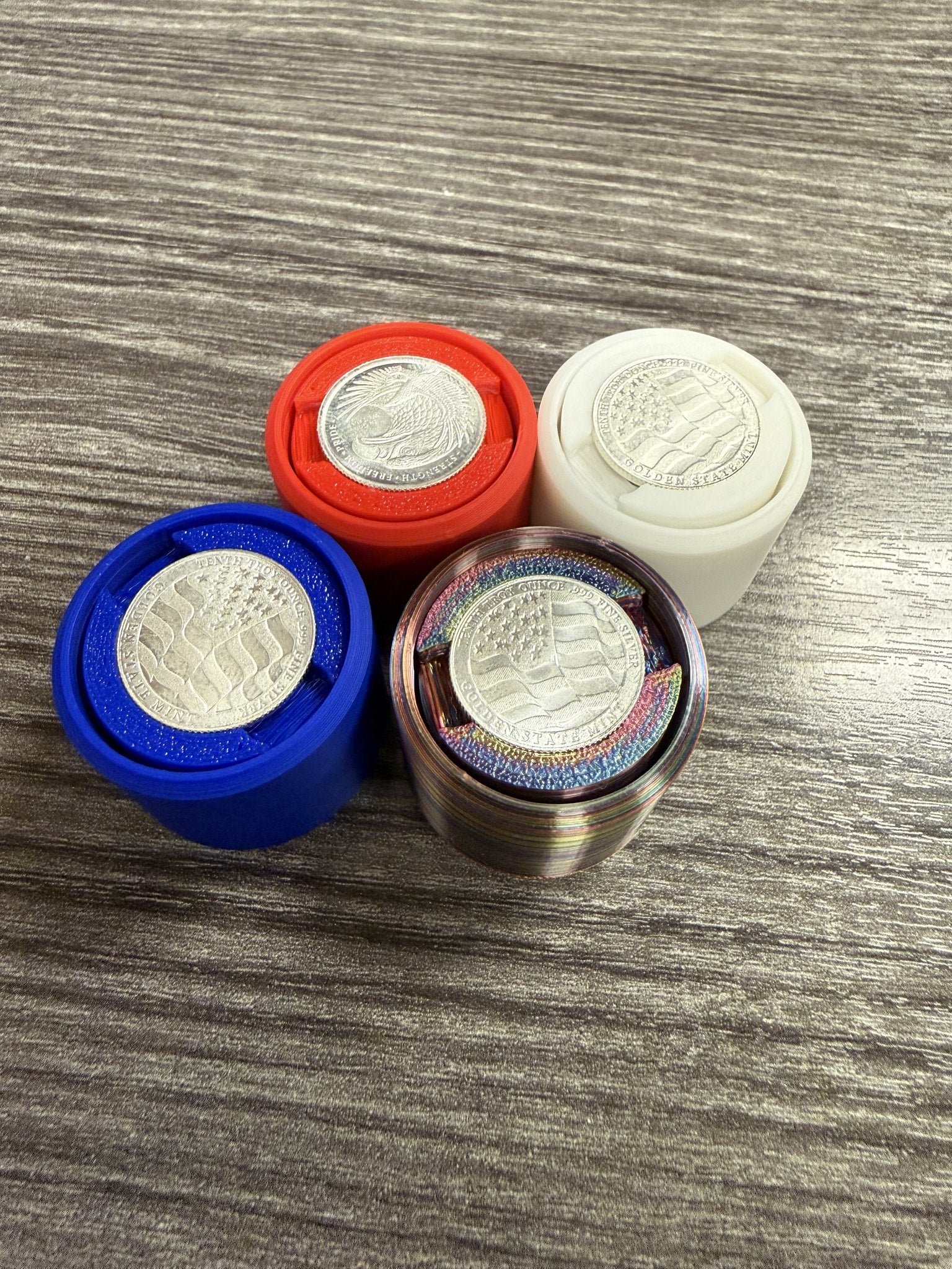 Four Silver Coin Fidget Clickers in white, multicolor silk, red and blue, each with a Golden State Mint silver round set in the face