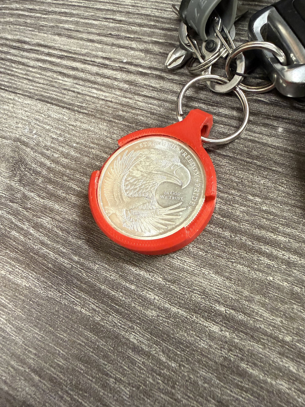 Angled view of the red Coin AirTag Hiding Keychain showing the snap-fit coin bezel