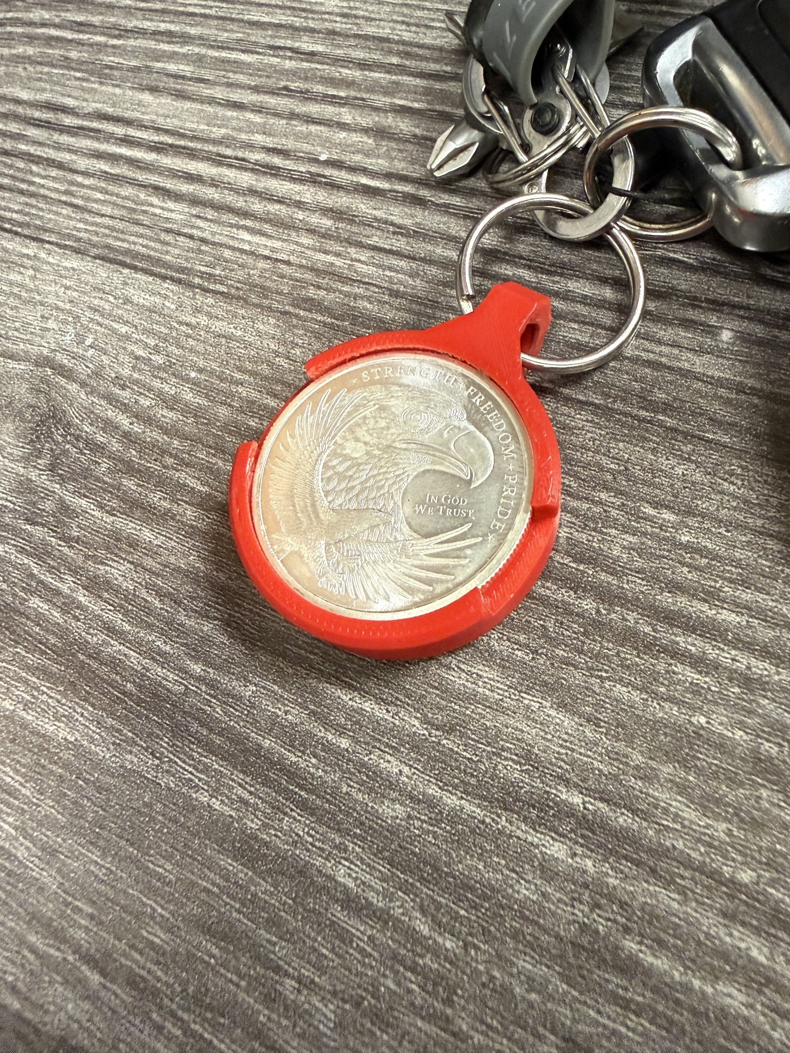Angled view of the red Coin AirTag Hiding Keychain showing the snap-fit coin bezel